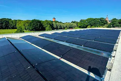 Zonnepanelen in lange rijen op het platte dak van een sporthal.